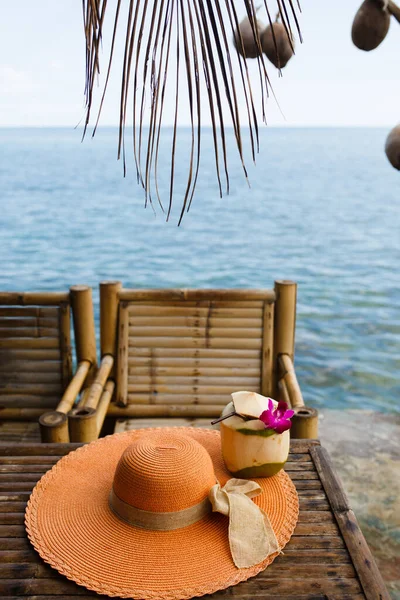 椰子汁和花一起喝 夏帽放在桌上 热带国家的假日 图库图片