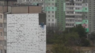 Yüksek irtifa iş. Adam kaplama, evi sıvama yüksek katlı inşaat üstünde çalışıyor. Yüksek katlı binaların duvarları ısınma. Yüksek katlı binaların duvarları ısınma. Yüksek irtifa eser bir yerleşim bölgesinde bulunmaktadır. Evler ısınma.