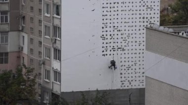 Yüksek irtifa eser bir yerleşim bölgesinde bulunmaktadır. Evler ısınma. Yüksek irtifa iş. Adam kaplama, evi sıvama yüksek katlı inşaat üstünde çalışıyor. Yüksek katlı binaların duvarları ısınma. Yüksek katlı binaların duvarları ısınma.