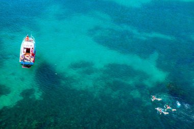 Hava su turkuaz lagün sıcak yaz gününde beyaz tekne ve insanlar etrafında tekne yüzme fotoğrafını.