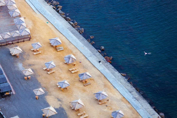 Aerial view of beach with umbrellas and turquoise sea with person alone swimming in water