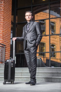 Seyahat çantası üzerinde takım elbise yakışıklı bir işadamı portresi