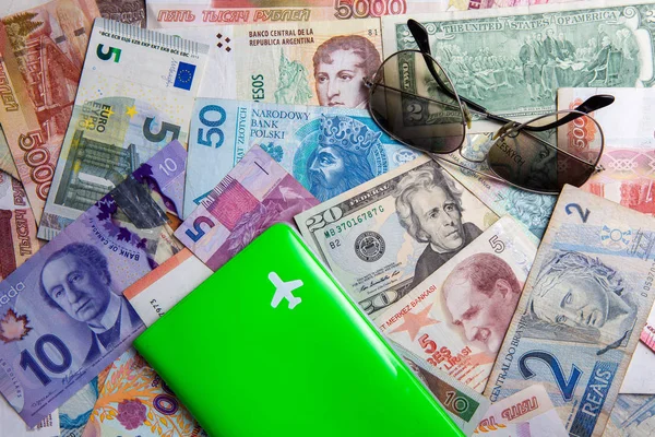 green passport cover with white symbol of plane and gradient shades on world currencies cash money background. travel worldwide concept