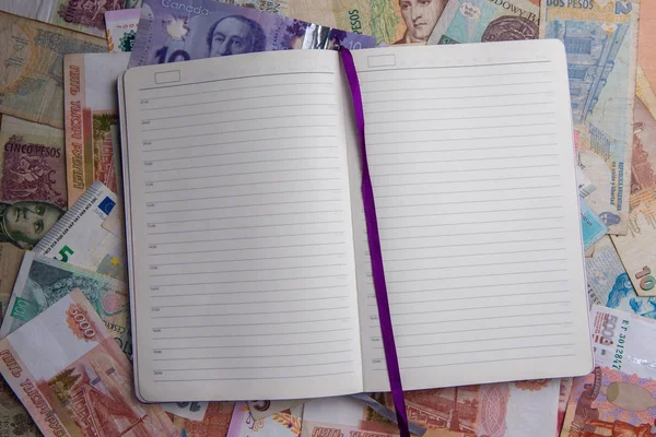 Otwarte codziennie planner lub pamiętnik, leżącego na tle pieniędzy walut świata — Zdjęcie stockowe