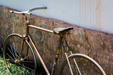 Beton duvarın yanında paslı eski bir bisiklet.