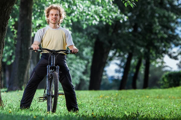 Portrait of happy man cyclist with his biycle in the park