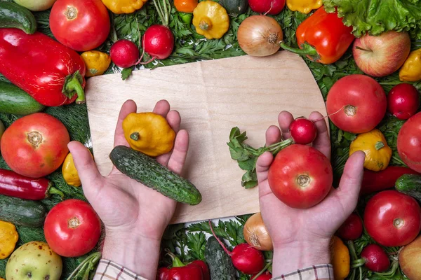 Man händer innehav grönsaker ovan skärbräda på vegetabiliska bakgrund — Stockfoto