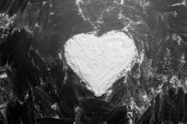 White flour heart shape in middle on black background texture dr — Stock Photo, Image