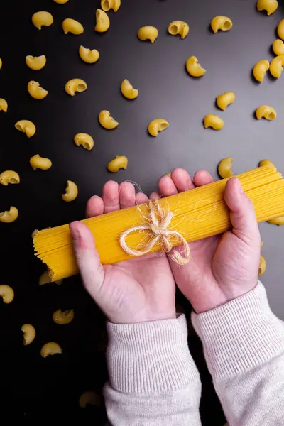 Hombre manos sosteniendo espaguetis y tubo rigate pasta italiana . — Foto de Stock