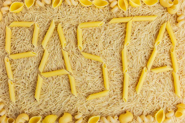 Ordet pasta tillverkad av penne rigate på en bakgrund av spån — Stockfoto