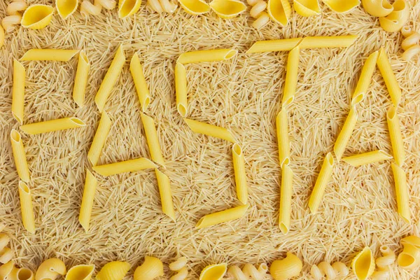 Palabra pasta hecha de penne rigate sobre un fondo de vermicelli — Foto de Stock