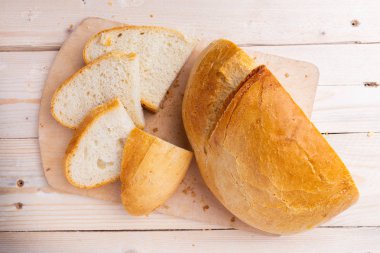 Beyaz ahşap arka plan üzerinde kesme tahtası üzerinde ekmek dilimlenmiş.