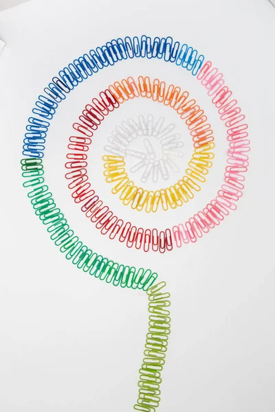 Figura espiral multicolorida de clipes de papel isolados em branco . — Fotografia de Stock