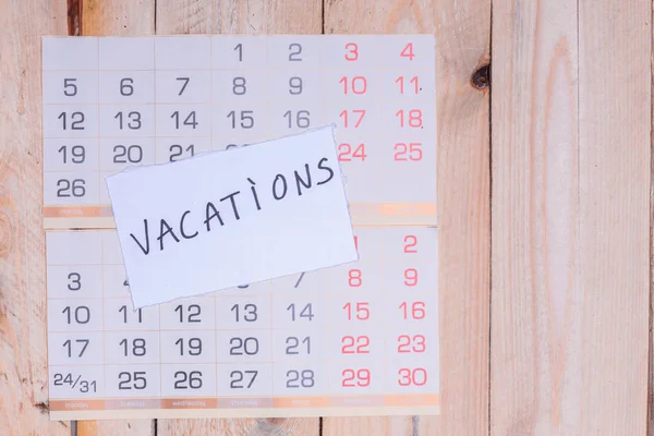 Vacations written on paper note on a wall calendar