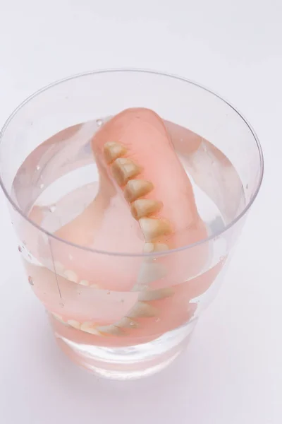 白い背景の上の水のガラスの義歯のクローズ アップ — ストック写真