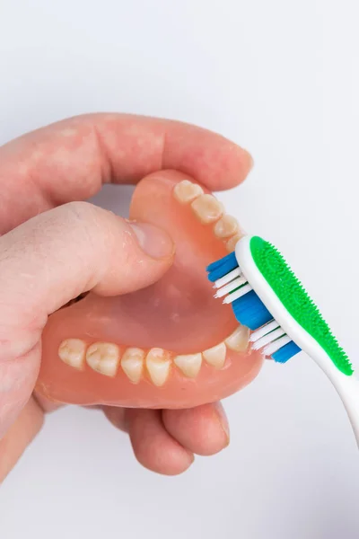 denture in man hand cleaning with tooth brush closeup top view