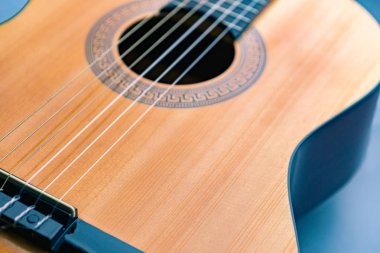 Akustik gitar sarı parlak ahşap güverte üzerinde mavi arka plan, parça, görünümü, seçici odak sığ derinliği parçası kavisli şekli