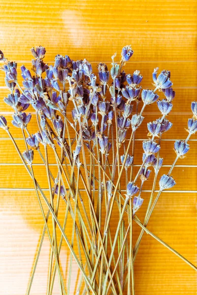 A musical instrument acoustic guitar, yellow wood deck decorated with dried bunch of lavender flowers on strings, closeup, fragment, top view. concept of music and nature.