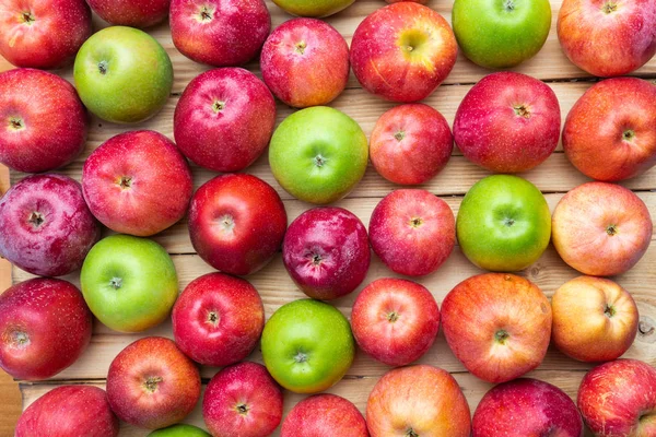 Cumulo di mele verdi e rosse non lavate mescolare su sfondo di legno — Foto Stock