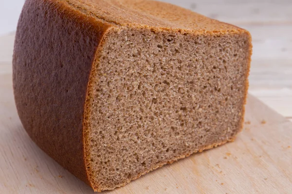 Μισό τούβλο καφέ ζυθοποιηθεί ψωμί από αλεύρι σίκαλης, σε ξύλινη επιφάνεια — Φωτογραφία Αρχείου