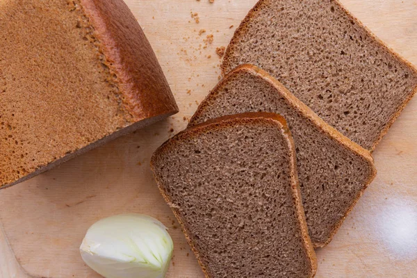 Sneetjes roggebrood baksteen bruin, ui en zout op houten bureau — Stockfoto