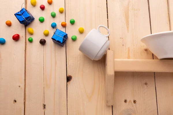 Bombones de colores y pequeñas cajas de regalo que se derraman de una taza de café que cae de la estantería — Foto de Stock