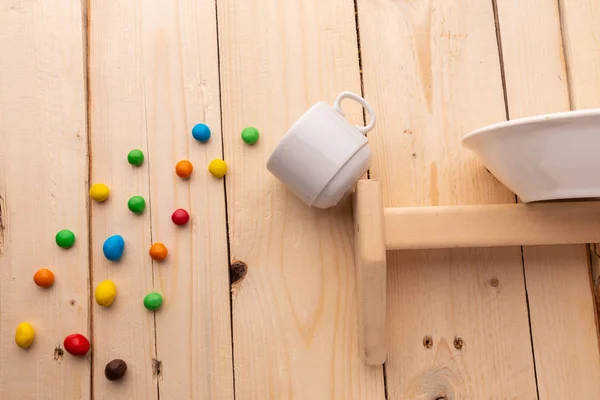 Bombones de colores que se derraman de una taza de café que cae de la estantería — Foto de Stock
