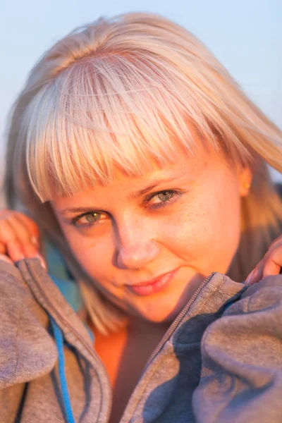 Junge Frau mit blonden Haaren im Kapuzenpulli bei Sonnenuntergang — Stockfoto