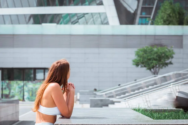 hipster girl is standing near the modern architecture building