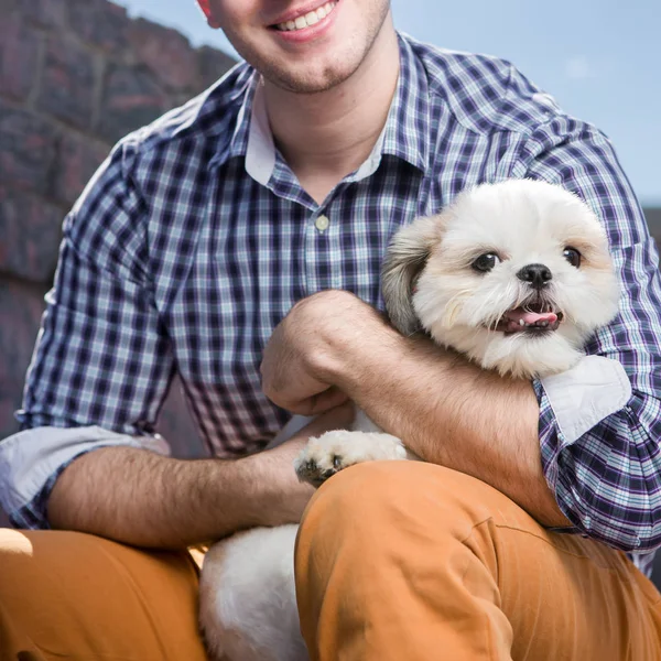 fashionable smiling man holding Small white dog