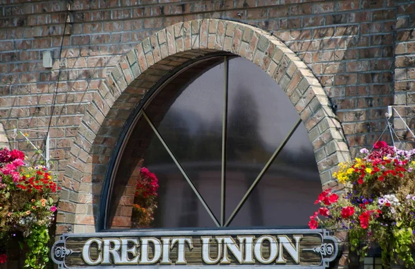 Window of a credit union in British Columbia surrounded by flower baskets