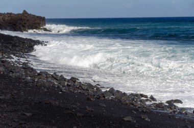Pohoiki plajının siyah kumlarının kenarında kaba sörf