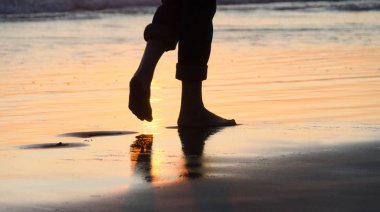 Feet of a beachgoer on sunset at Newport Pier beach 