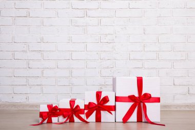 Beyaz tuğla duvarın üzerinde Noel hediyesi kutuları