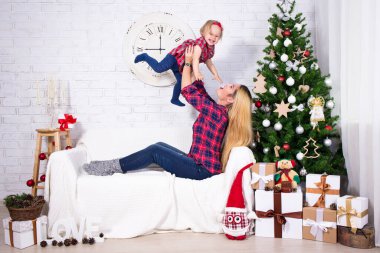 Noel ve mutluluk. Genç anne küçük kızıyla dekore edilmiş oturma odasında oynuyor.
