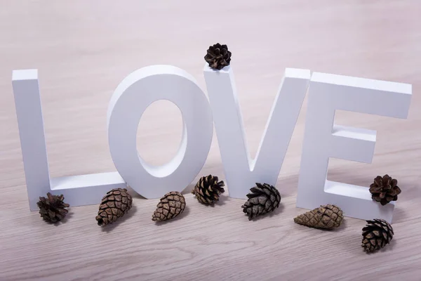 愛と冬のコンセプト テーブルの上に木製の手紙と松のコーン — ストック写真