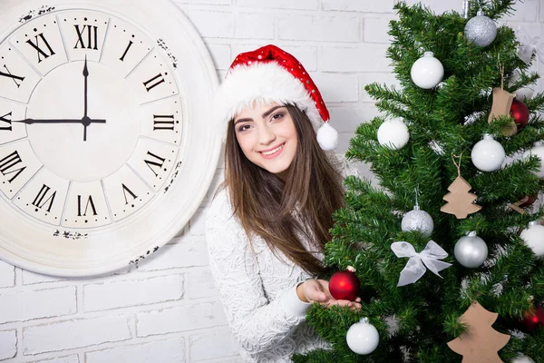 Niedliches Mädchen Mit Weihnachtsmütze Mit Geschmücktem Weihnachtsbaum Und Alter Uhr — Stockfoto