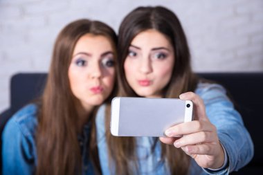 Modern akıllı telefonla fotoğraf çeken iki komik kız.