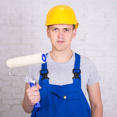 Beyaz tuğla duvarın üzerinde paten fırçası olan genç bir ressamın portresi