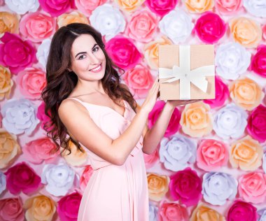 Doğum günü konsepti. Mutlu, hediye kutusu olan güzel bir kadın. Renkli çiçeklerin arkasında duruyor.