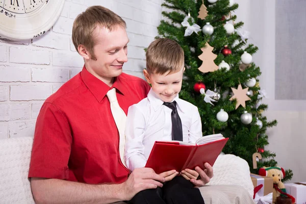 Glad Ung Far Läser Bok För Sin Son Framför Julgranen — Stockfoto