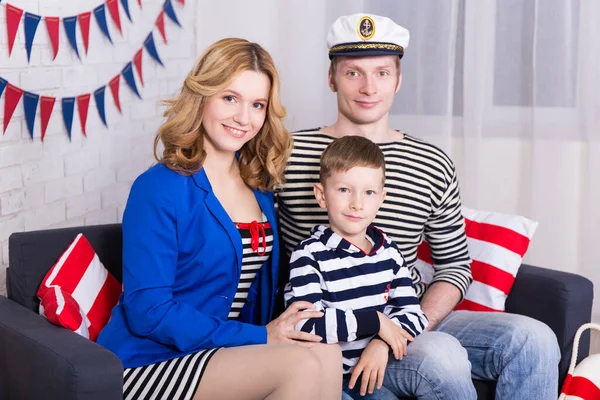 快乐的父母和身穿水兵制服的小儿子坐在家里装饰过的客厅里 — 图库照片