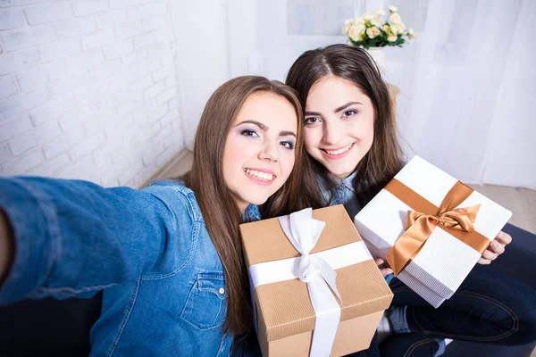 2人の幸せな美しい女性がリビングでプレゼントと一緒に写真を撮る — ストック写真