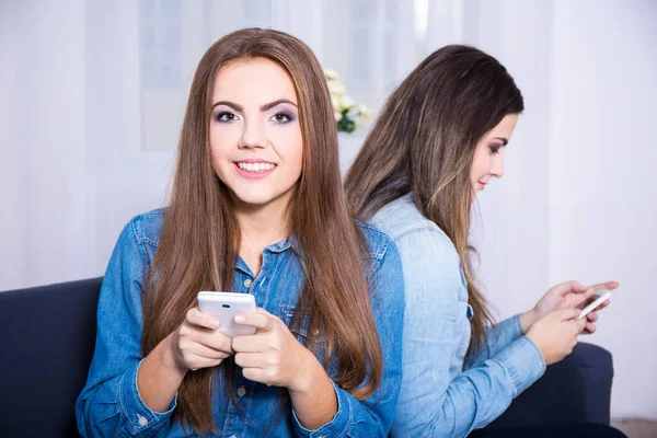 友情と電話中毒の概念 自宅でスマートフォンを使っている2人の若い女性 — ストック写真
