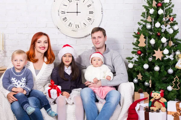 クリスマスツリーの前にギフトボックスを持つ若い幸せな家族 — ストック写真
