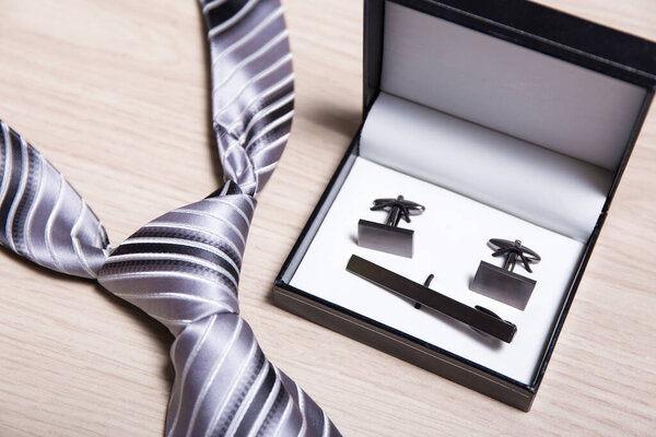 close up of tie and cufflinks on wooden table