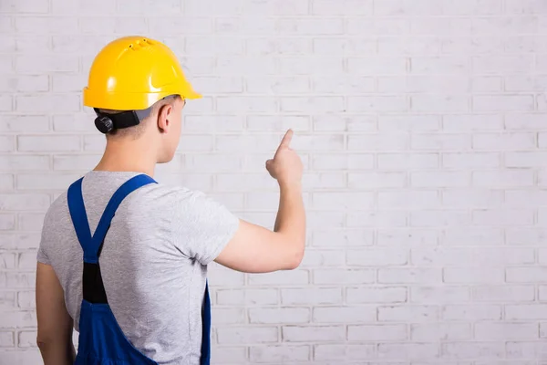Back View Man Blue Builder Uniform Pointing White Brick Wall — Stock Photo, Image