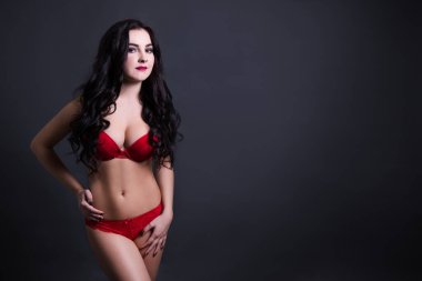 Kırmızı dantelli iç çamaşırlı seksi ve büyük model fotokopi alanı ile siyah arkaplan üzerinde poz veriyor