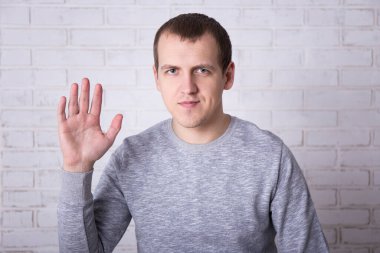 Beyaz tuğla duvarda selam veren genç adamın portresi