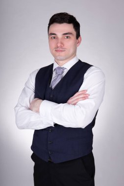 Gri arka planda poz veren genç iş adamı